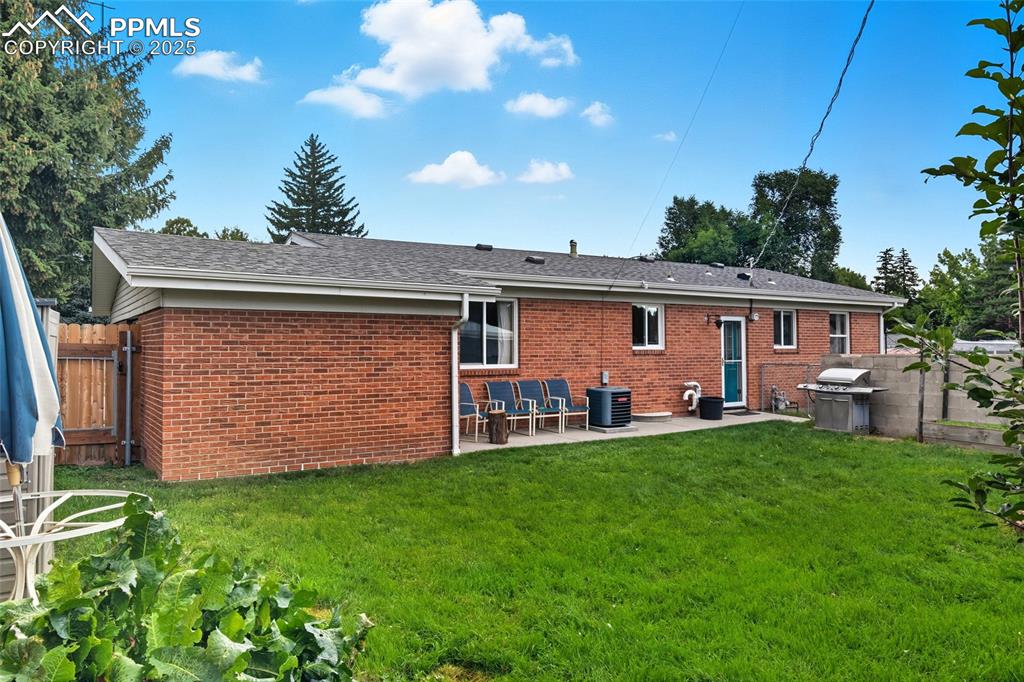 Image 33 of 39: Back of house featuring brick siding, a patio area, and roof with shingles