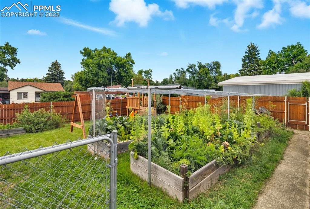 Image 35 of 39: Fenced backyard featuring a vegetable garden