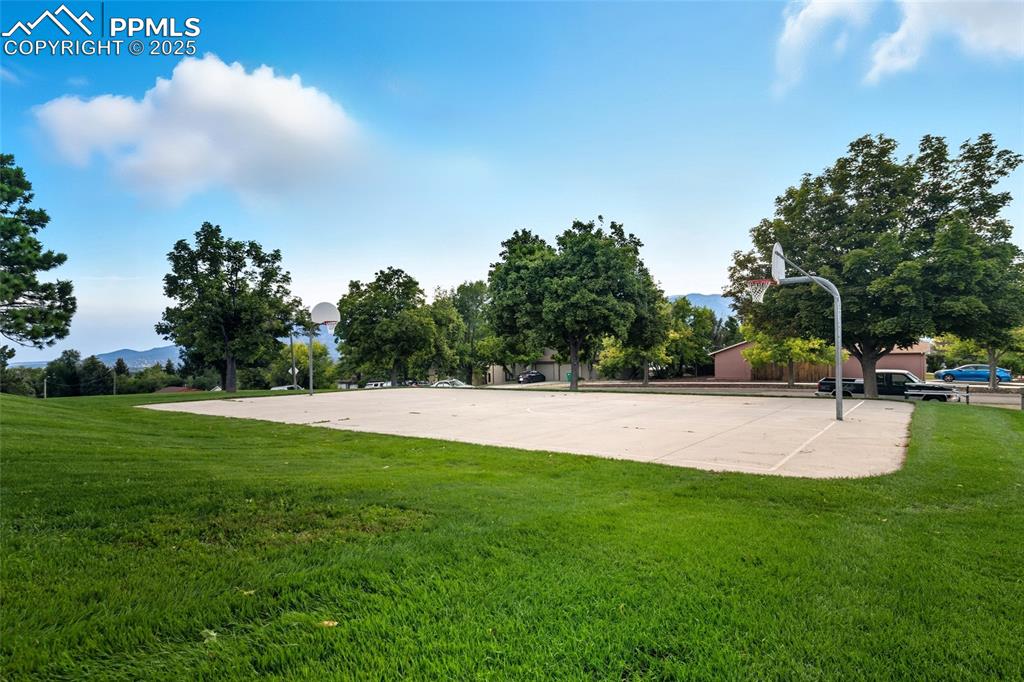 Image 39 of 39: View of community with community basketball court, a yard, and a mountain v