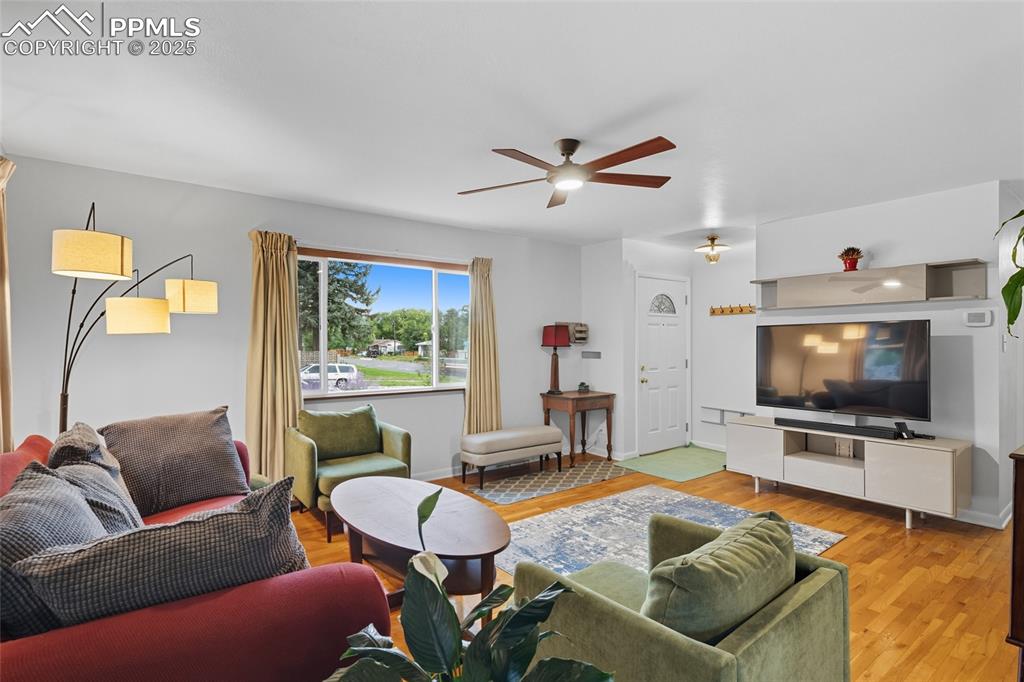 Image 7 of 39: Living room with light wood finished floors and ceiling fan