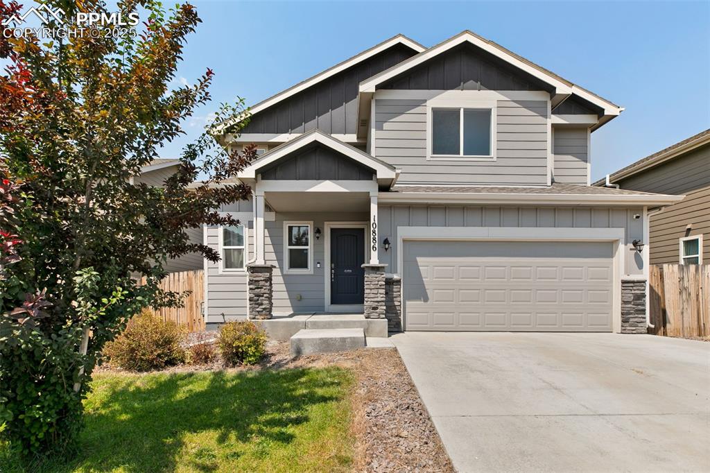 Caption: Craftsman-style home featuring board and batten siding, an attached garage, stone siding, and concre