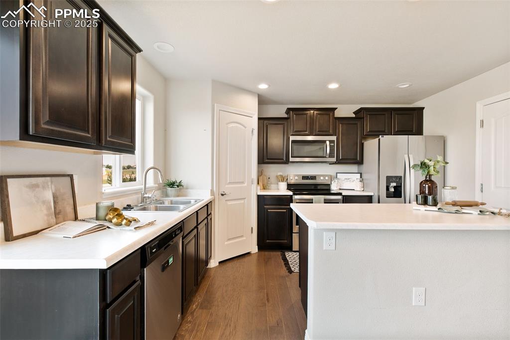 Image 11 of 28: Kitchen with appliances with stainless steel finishes, dark brown cabinetry