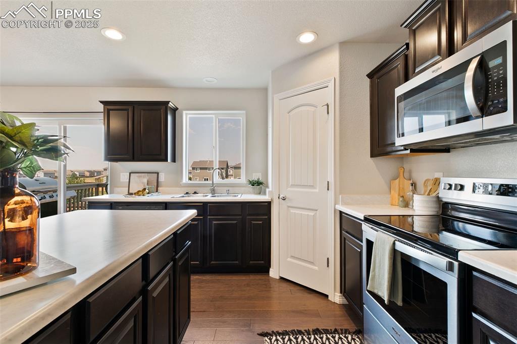 Image 13 of 28: Kitchen with appliances with stainless steel finishes, light countertops, d