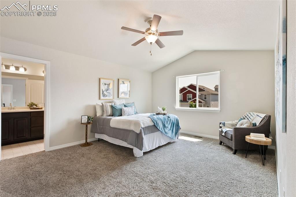 Image 15 of 28: Bedroom featuring light carpet, lofted ceiling, ceiling fan, and ensuite ba