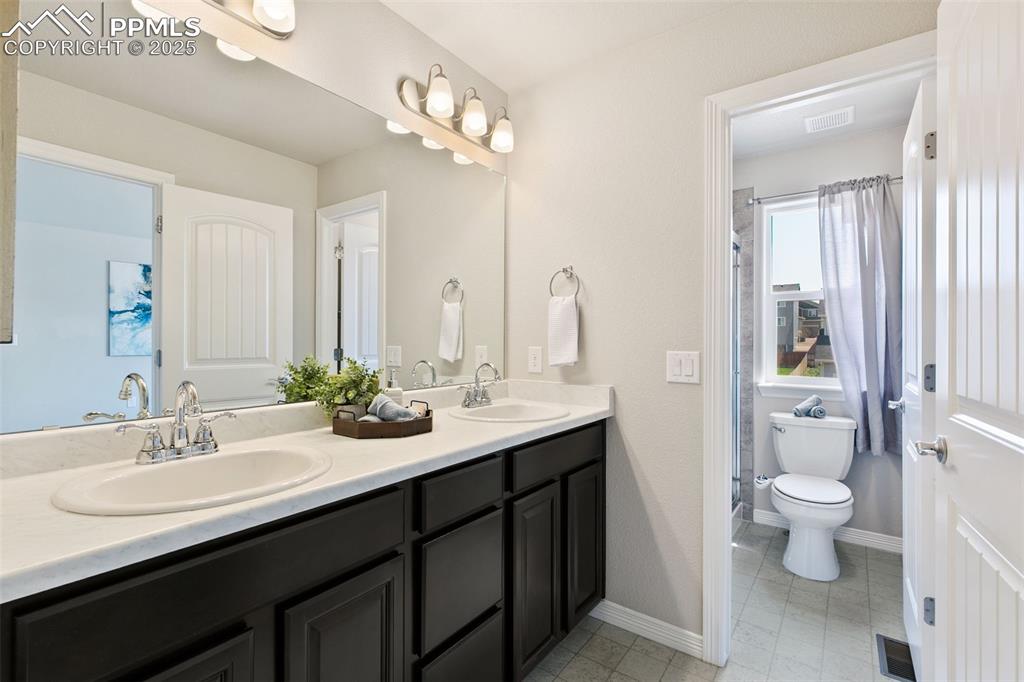 Image 17 of 28: Bathroom featuring double vanity and a shower with shower curtain
