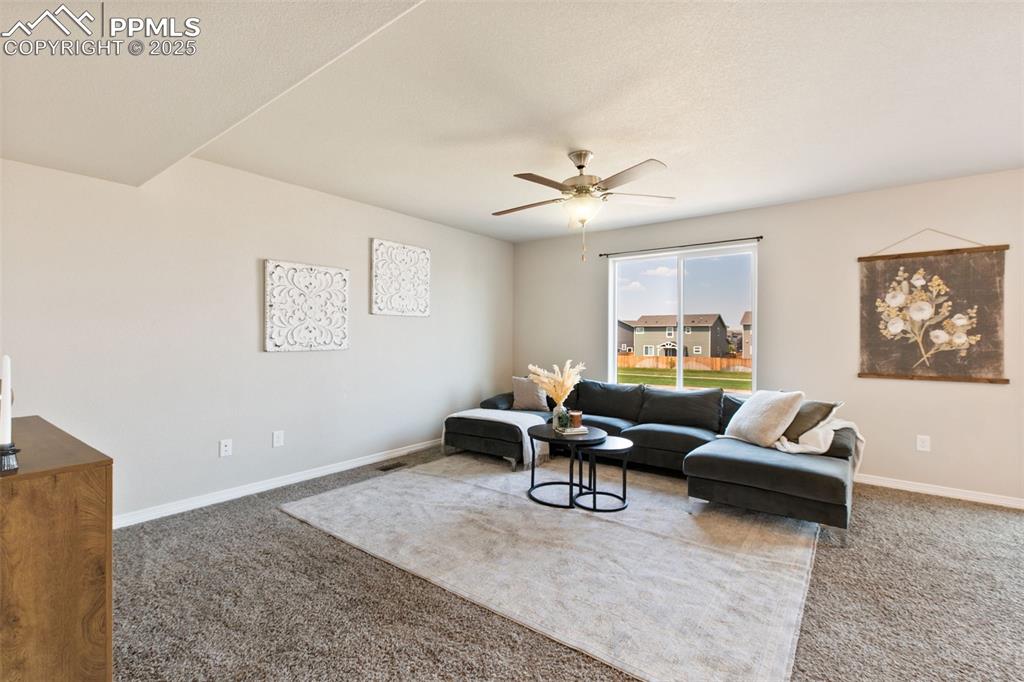 Image 4 of 28: Carpeted living room with baseboards and a ceiling fan
