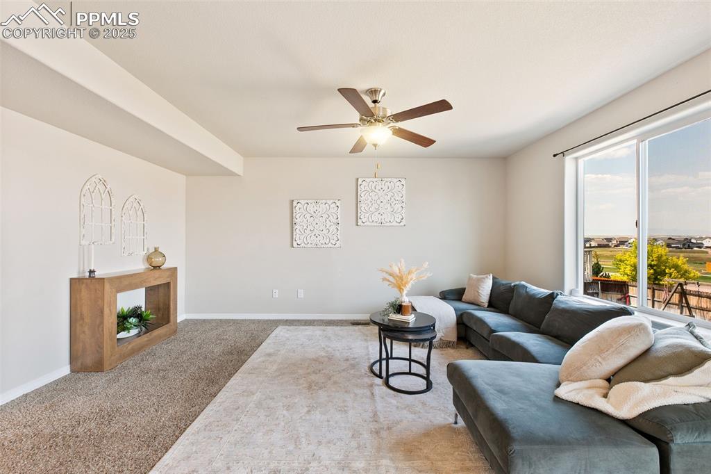 Image 6 of 28: Carpeted living room featuring baseboards and ceiling fan