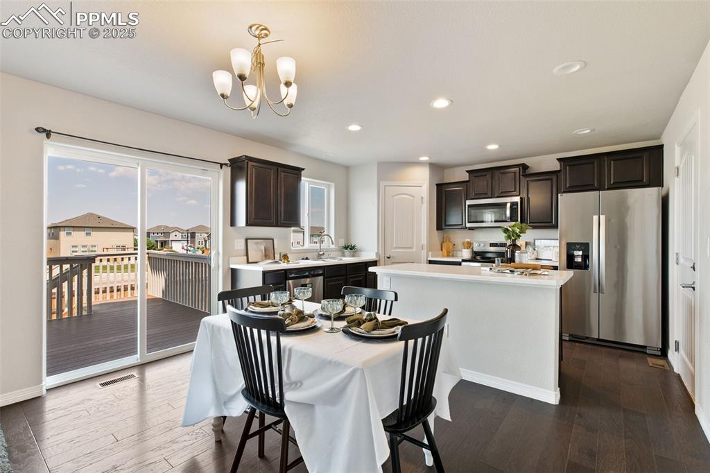 Image 8 of 28: Dining room featuring dark wood-style floors, recessed lighting, and a chan