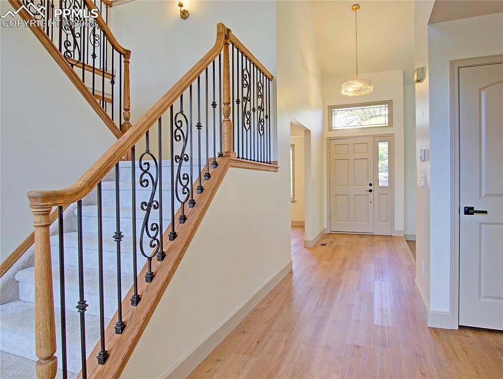 Image 12 of 50: Entrance foyer featuring wood finished floors, a towering ceiling, and stai