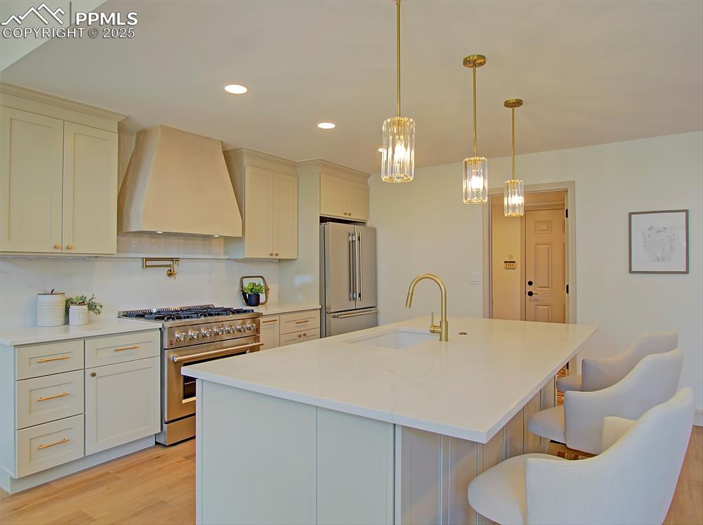 Image 19 of 50: Kitchen with high quality appliances, custom range hood, light wood-style f