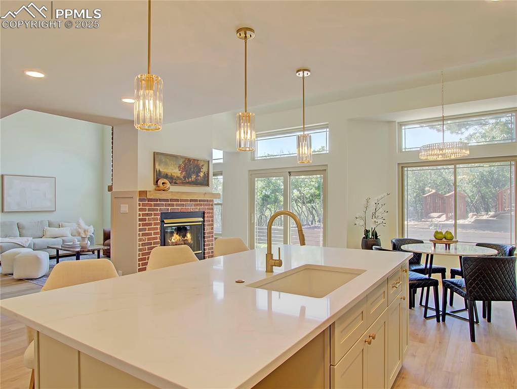 Image 21 of 50: Kitchen featuring a chandelier, light wood-type flooring, a fireplace, open