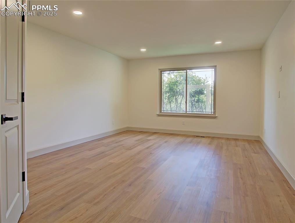 Image 25 of 50: Main level Bedroom with light wood-type flooring and recessed lighting