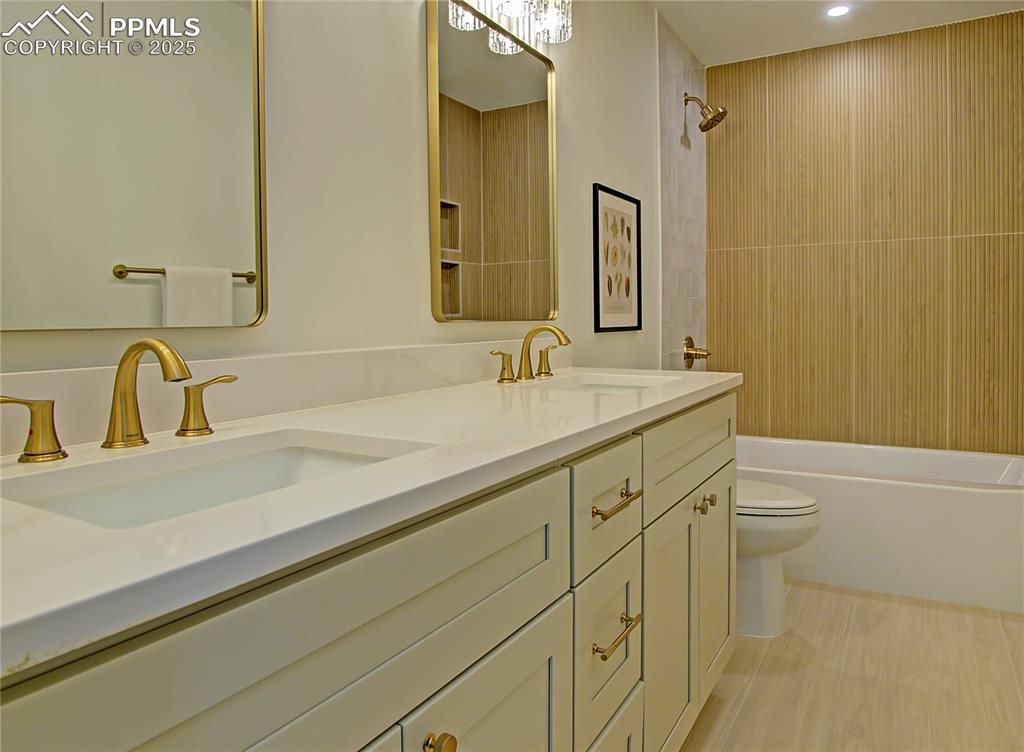 Image 39 of 50: Bathroom with double vanity, shower combination, and recessed lighting