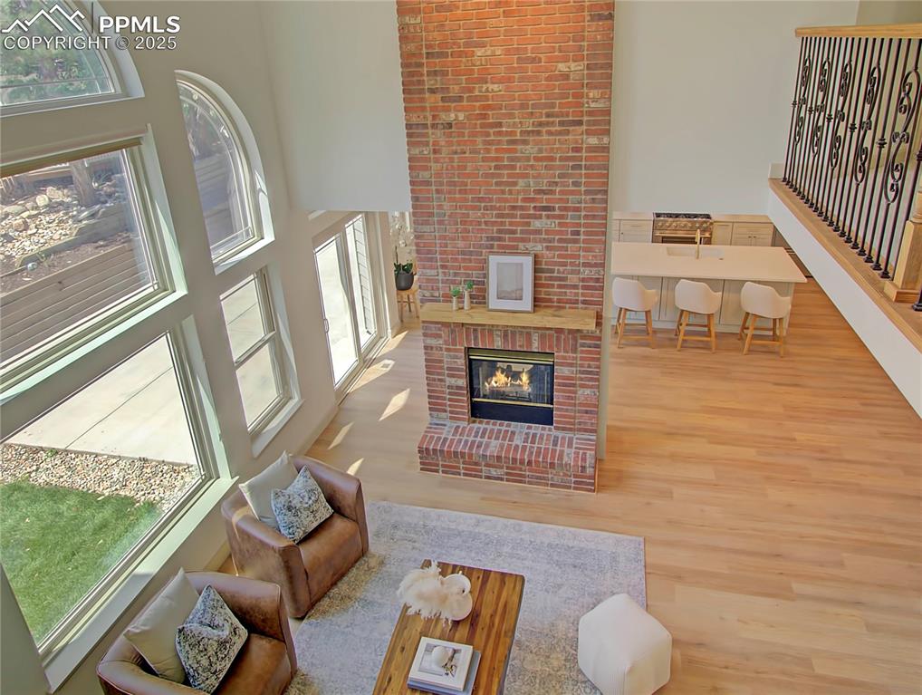 Image 40 of 50: Family room with wood finished floors, a fireplace, and a towering ceiling