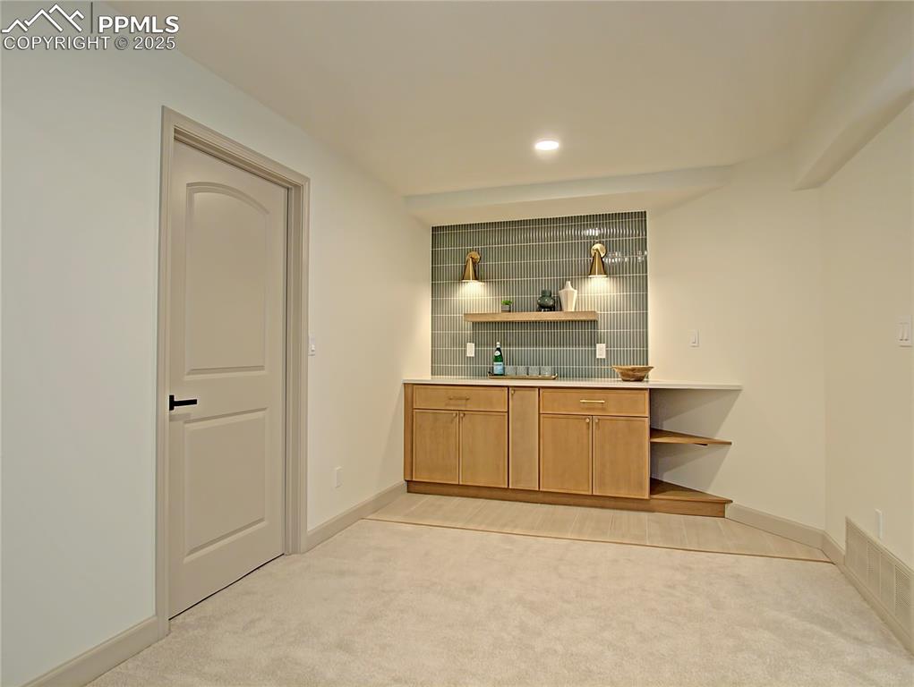 Image 42 of 50: Basement bar with light carpet, decorative backsplash, and recessed lightin