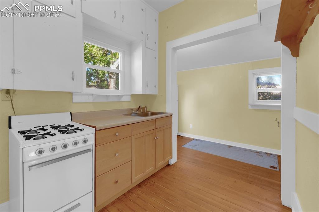 Image 14 of 28: Kitchen with white range with gas cooktop, light wood-style flooring, light