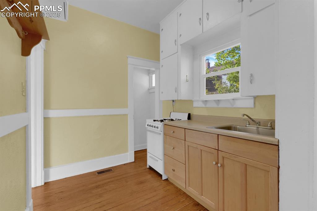 Image 15 of 28: Kitchen featuring light brown cabinets, white range with gas cooktop, light