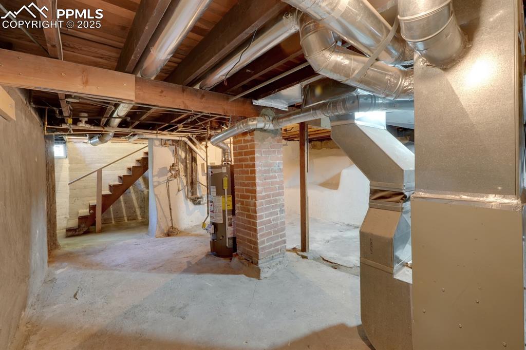 Image 23 of 28: Unfinished basement with heating unit, stairway, and gas water heater