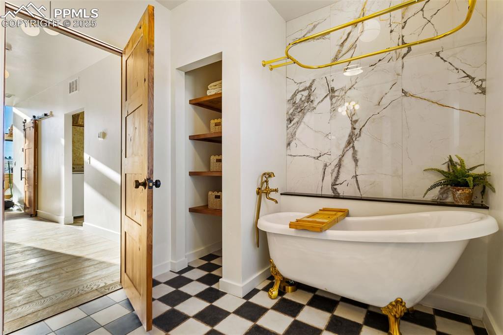 Image 25 of 49: Full bathroom featuring a freestanding tub and built in shelves