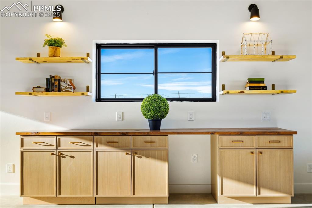 Image 32 of 49: Kitchen with open shelves, light brown cabinetry, and wood counters