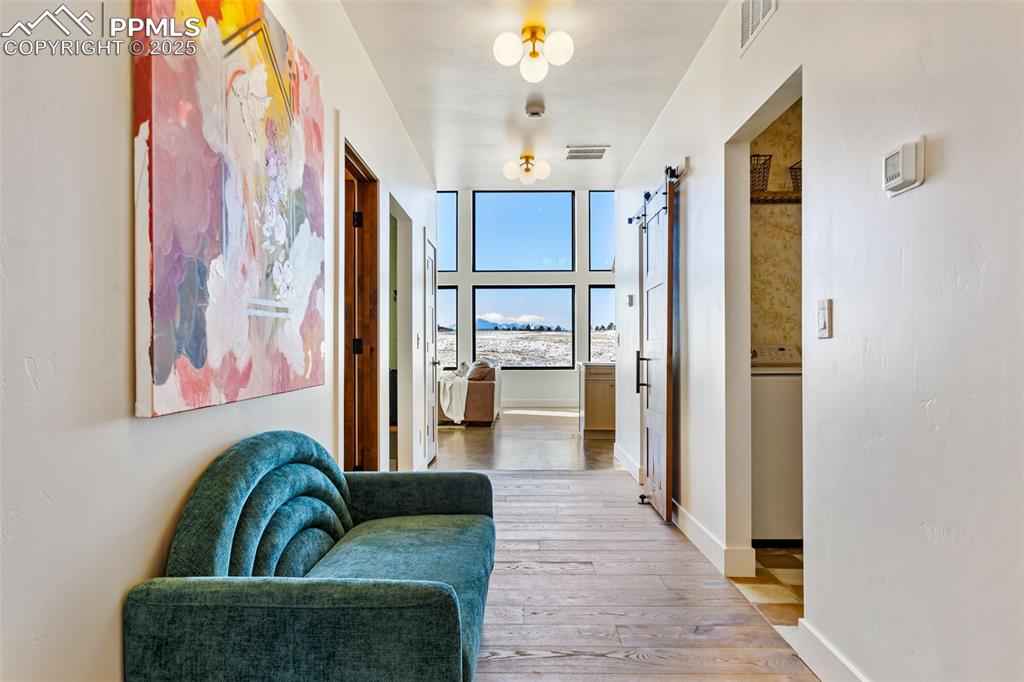 Image 33 of 49: Hallway with a barn door, light wood-type flooring, and washer / clothes dr