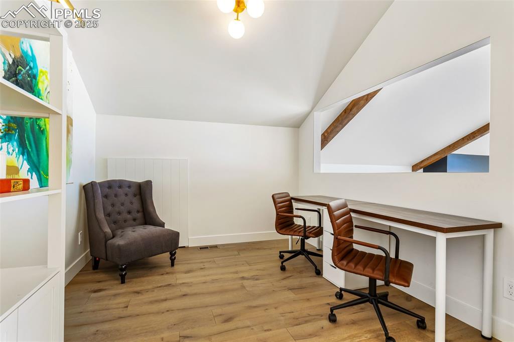 Image 35 of 49: Office space with light wood-style flooring and vaulted ceiling