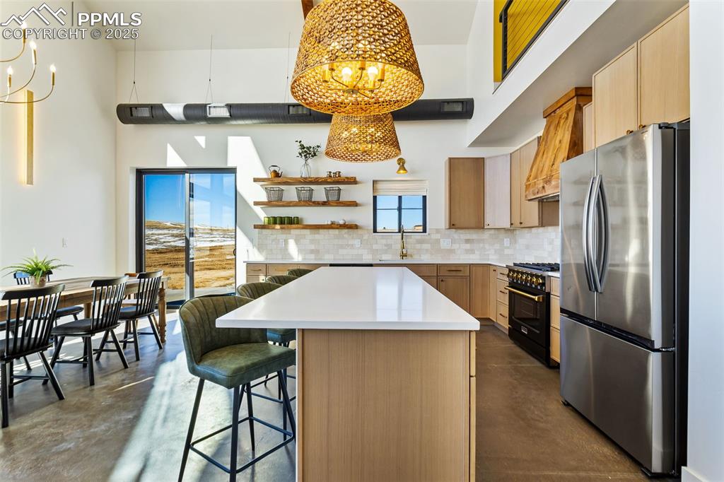 Image 8 of 49: Kitchen with freestanding refrigerator, finished concrete flooring, a chand