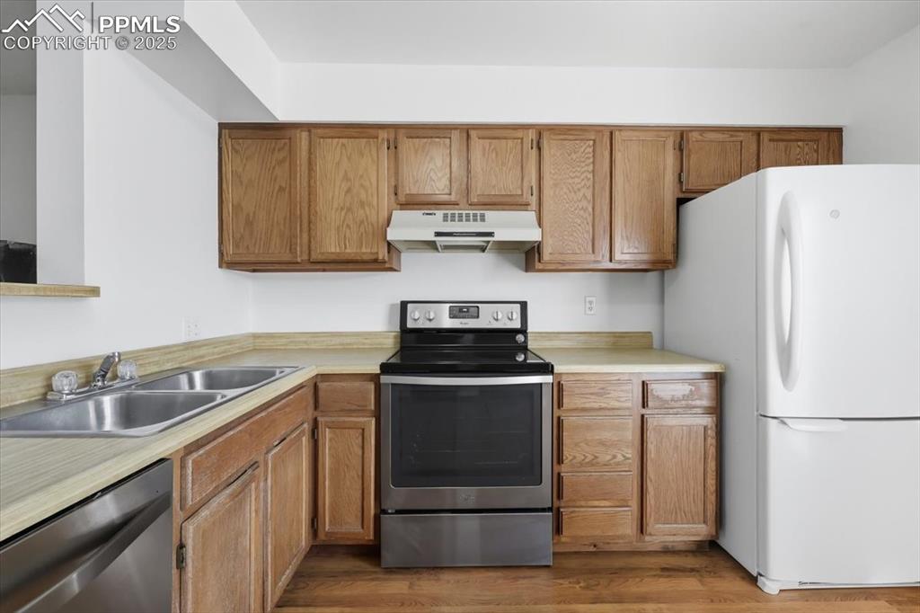 Image 11 of 34: Kitchen with stainless steel appliances, under cabinet range hood, light co