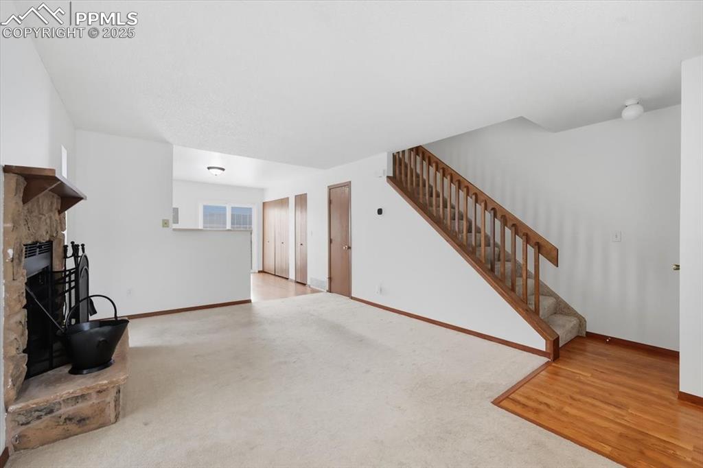 Image 6 of 34: Unfurnished living room with a fireplace with raised hearth, light wood-sty