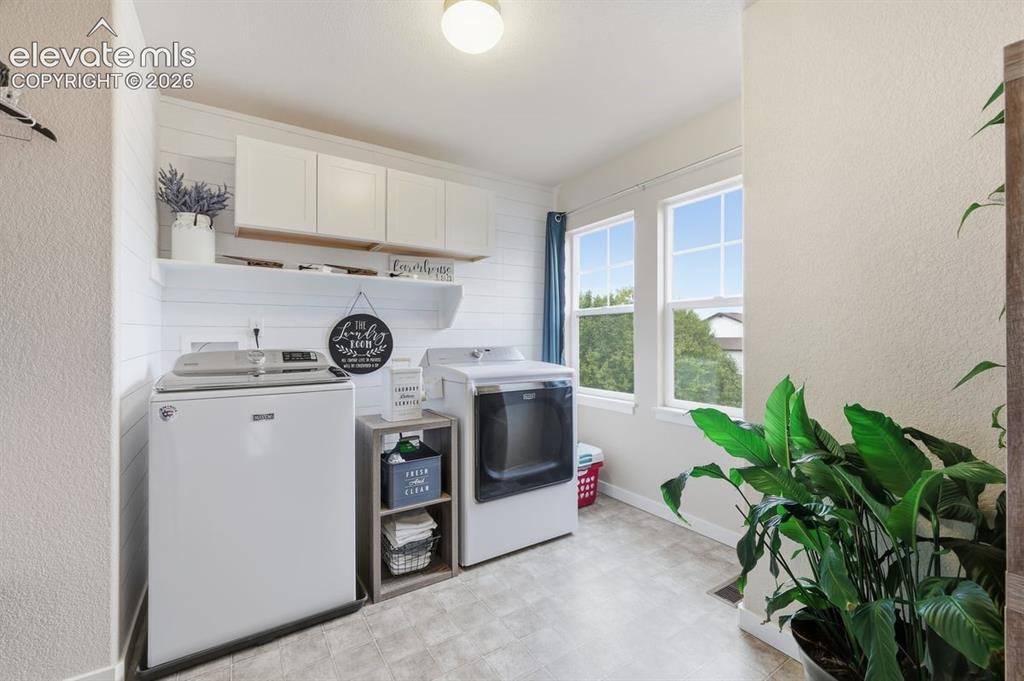 Image 15 of 50: upstairs laundry room with accent shiplap wall and upper cabinets for stora
