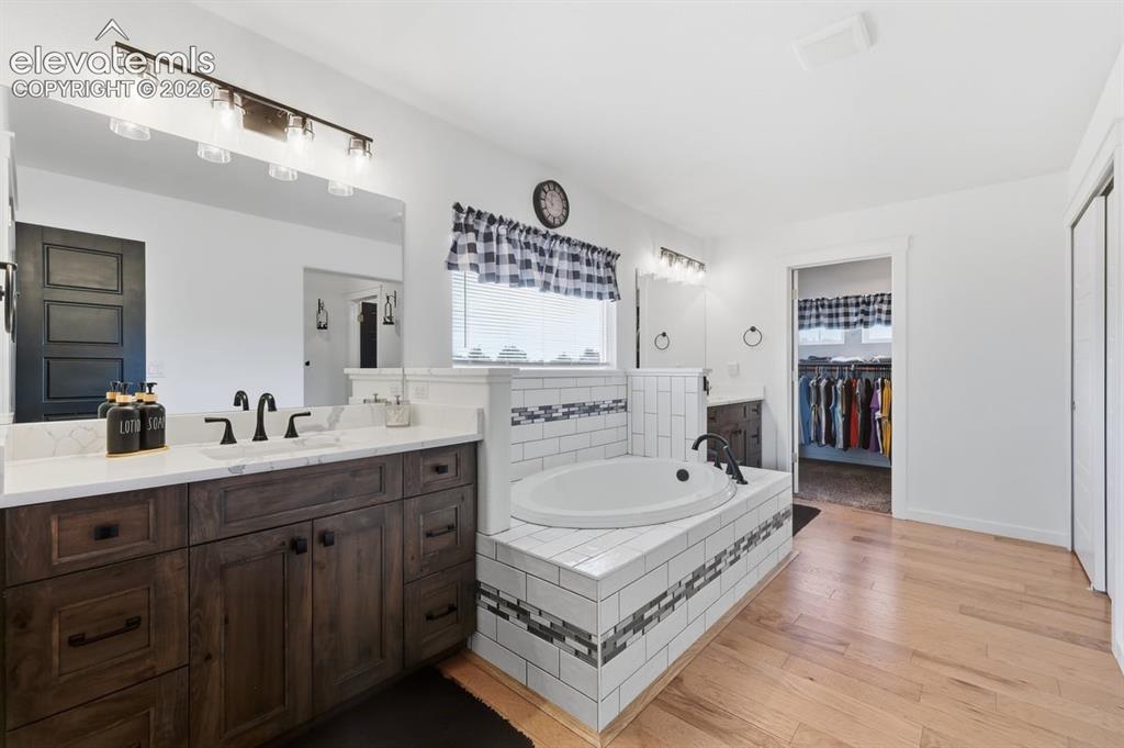 Image 18 of 50: separate sinks, quartz countertops, and wood flooring