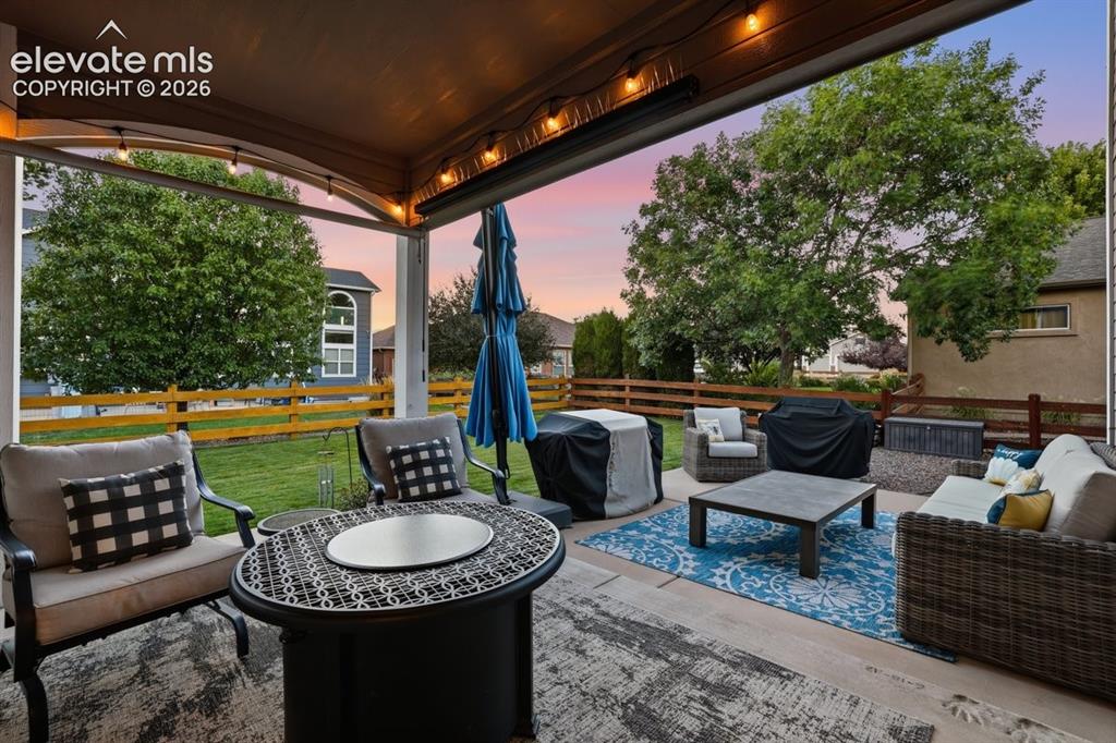 Image 3 of 50: private covered back patio overlooking a well manicured backyard space