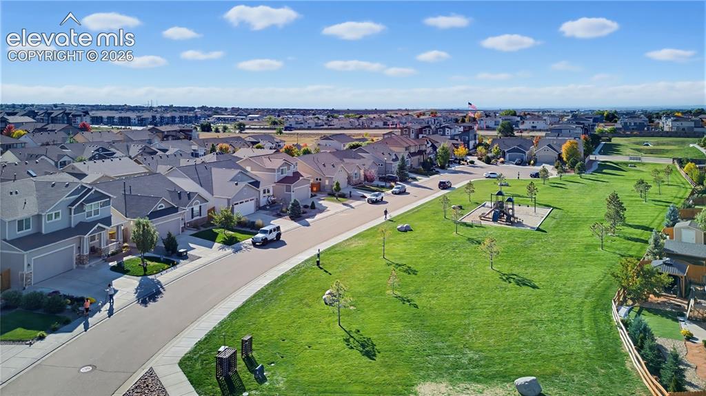 Image 13 of 50: Aerial perspective featuring expansive manicured green space, paved street 