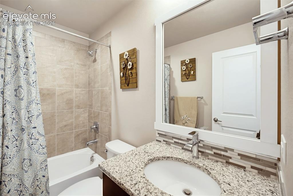 Image 16 of 50: Bathroom featuring a speckled stone-finish countertop, undermount sink, mul