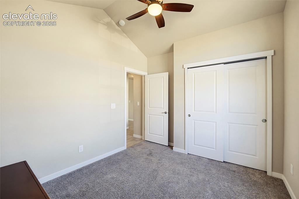 Image 21 of 50: Vaulted ceiling featuring a central lighted ceiling fan, carpeted flooring,