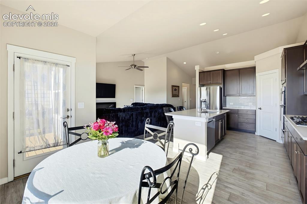 Image 26 of 50: Open-concept kitchen featuring dark-tone cabinetry, stone-surfaced countert