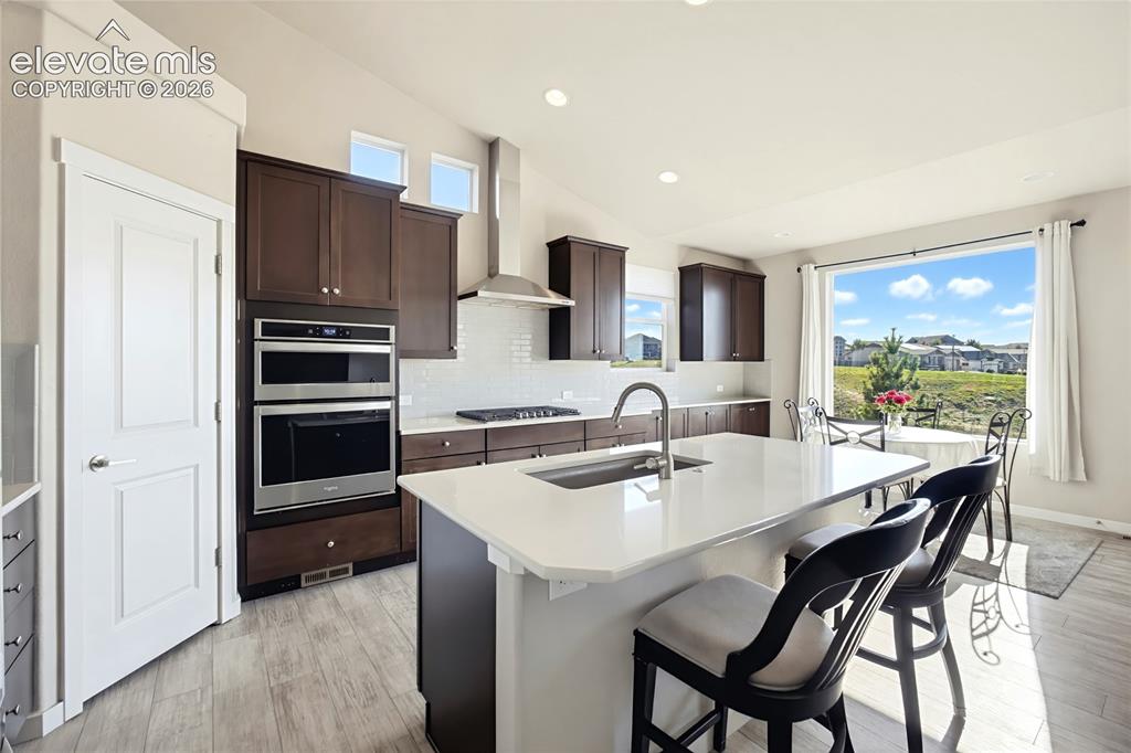 Image 27 of 50: Kitchen featuring a central island with a quartz countertop, dark wood-fini