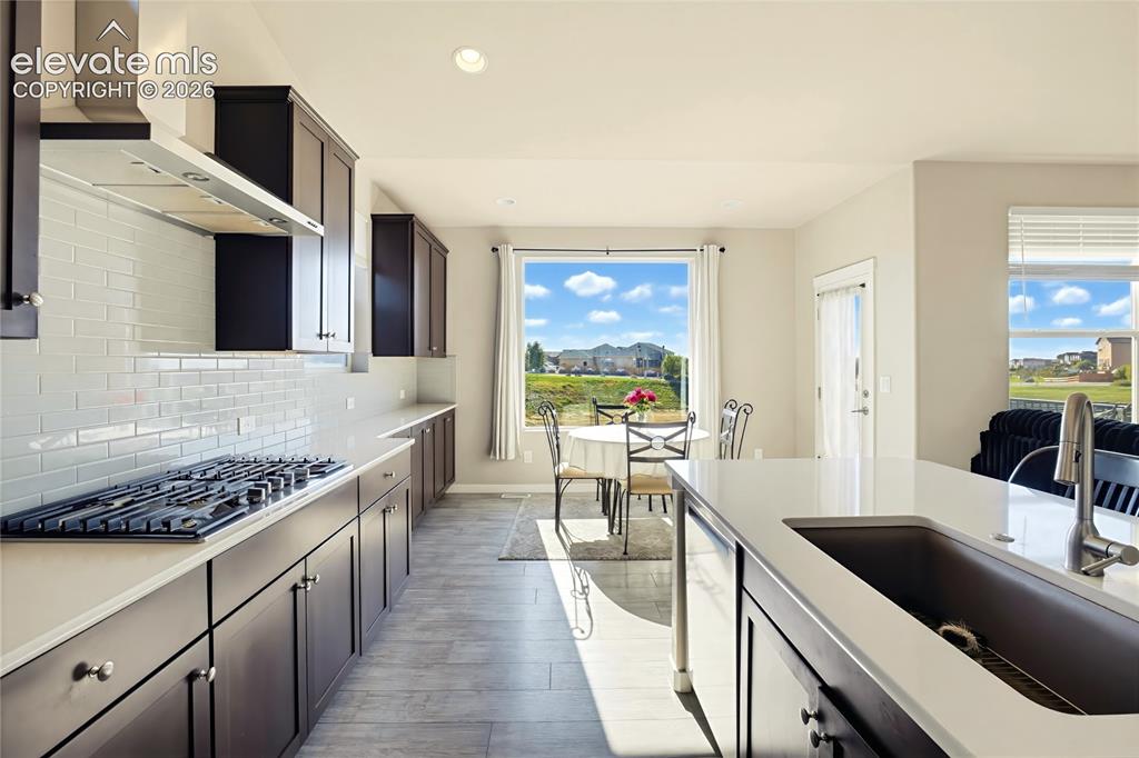 Image 30 of 50: Kitchen featuring dark cabinetry, expansive stone-surface countertops, subw