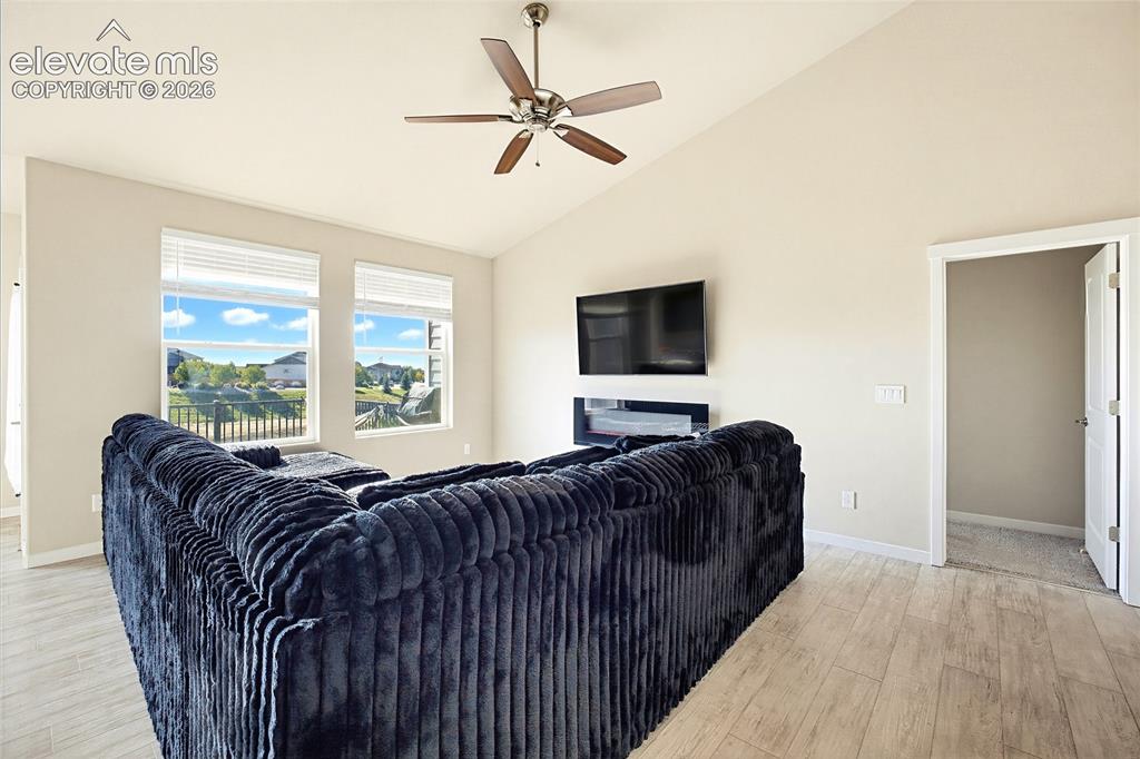 Image 31 of 50: Vaulted ceilings, wood-finish flooring, wall-mounted electric fireplace, an
