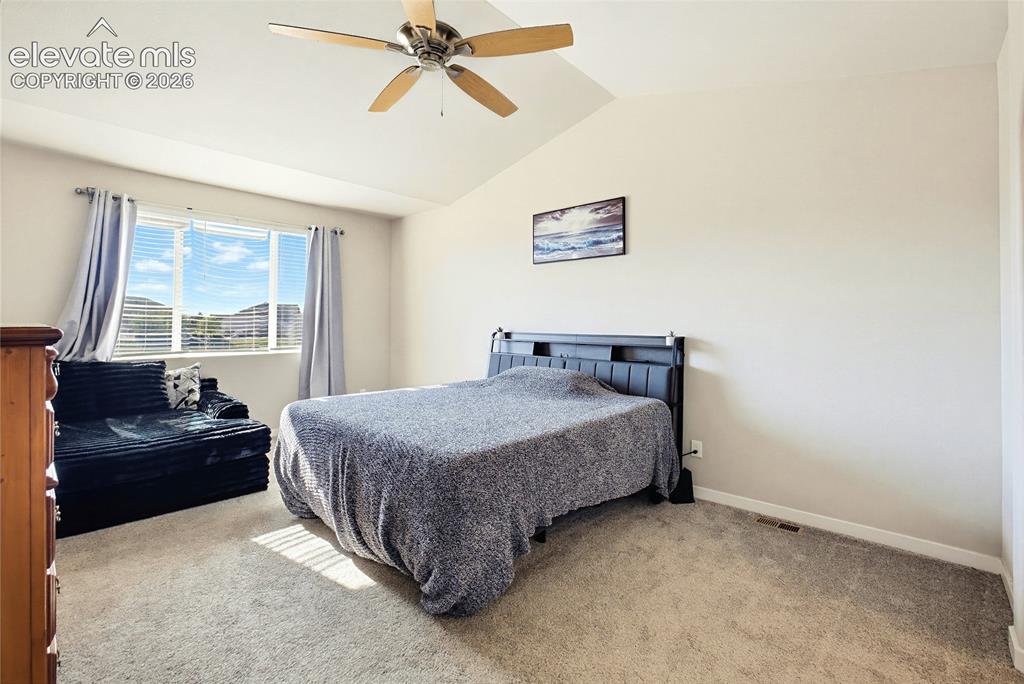 Image 33 of 50: Vaulted ceilings featuring a central ceiling fan, carpeted flooring, and a 