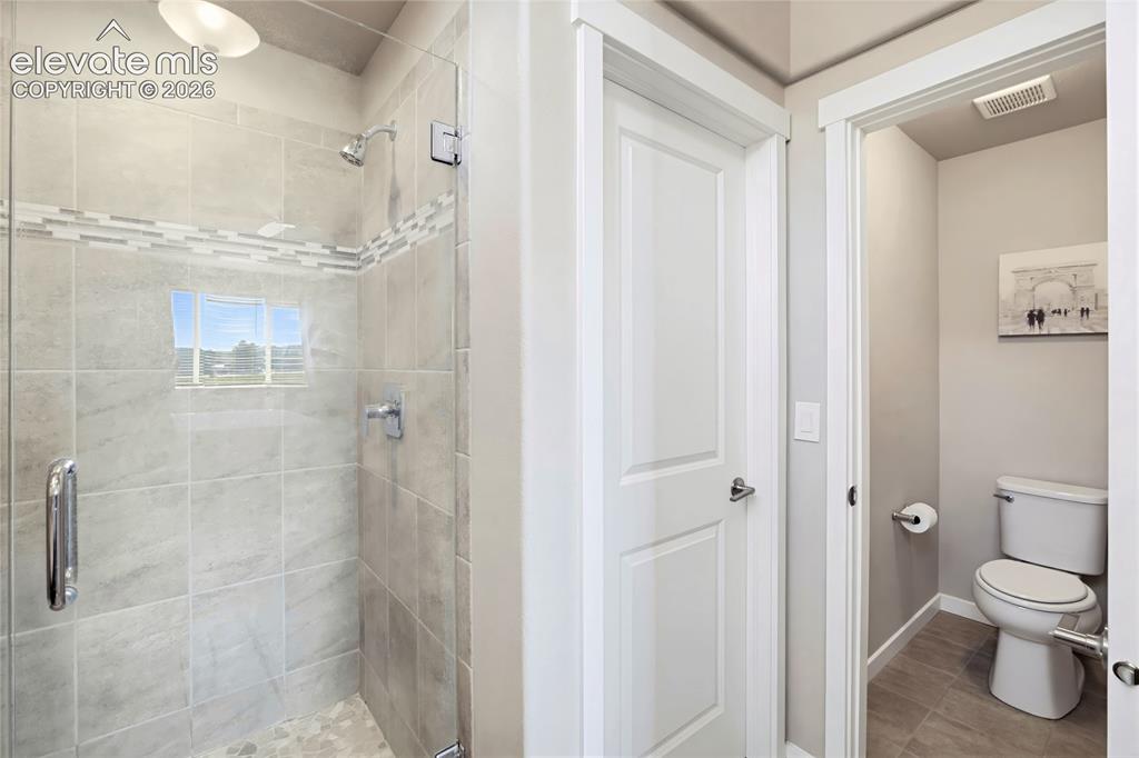 Image 38 of 50: Walk-in shower with floor-to-ceiling tile, decorative mosaic inlay, glass e