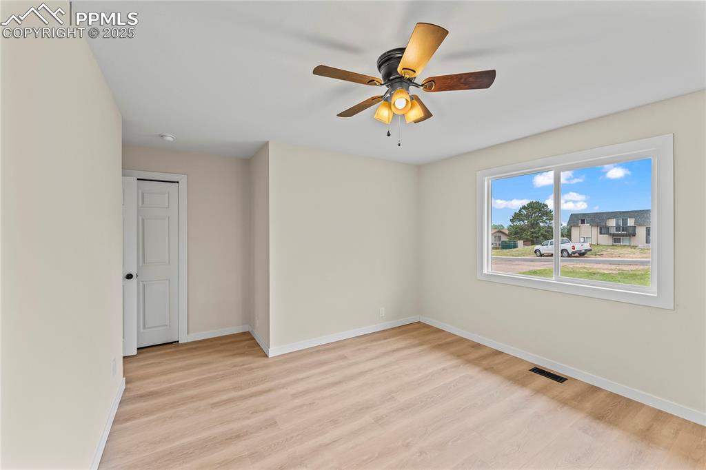 Image 14 of 34: Empty room featuring light wood-style floors and ceiling fan