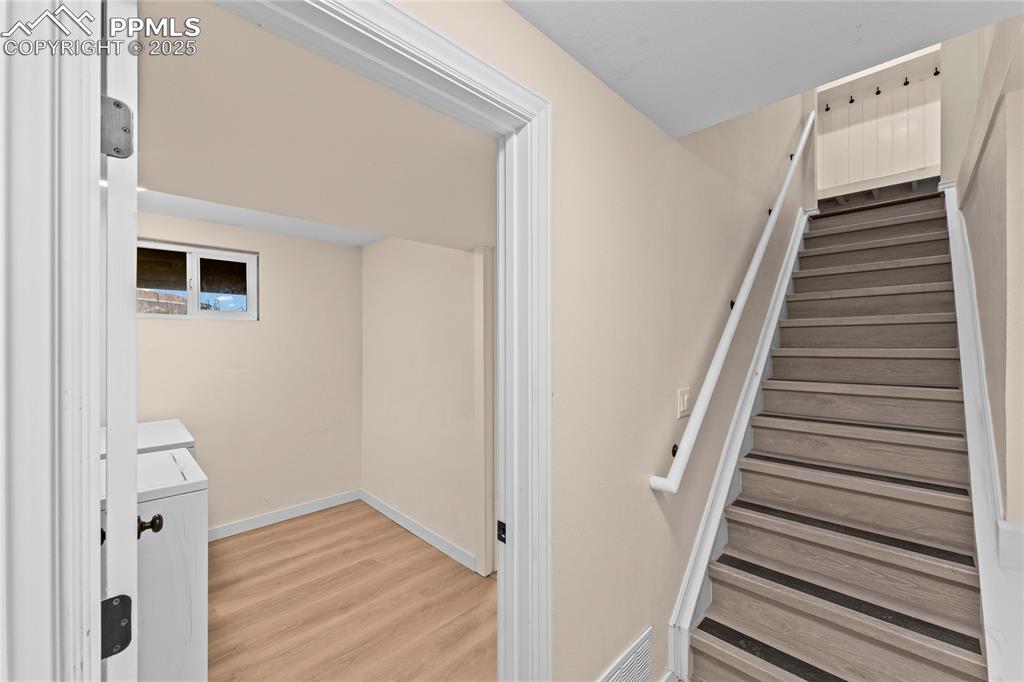 Image 16 of 34: Stairway with washing machine and dryer and wood finished floors