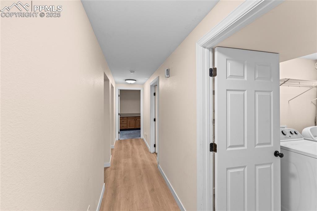 Image 17 of 34: Corridor featuring separate washer and dryer and light wood finished floors
