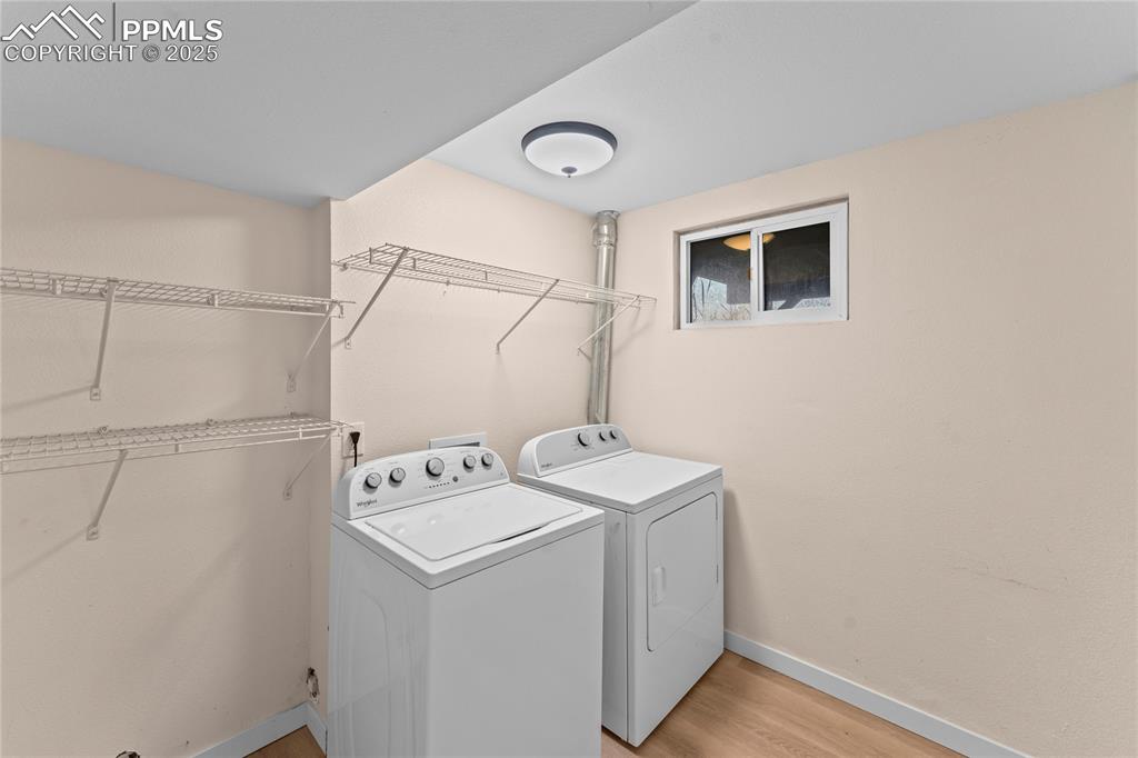 Image 18 of 34: Laundry room with washer and clothes dryer and light wood finished floors