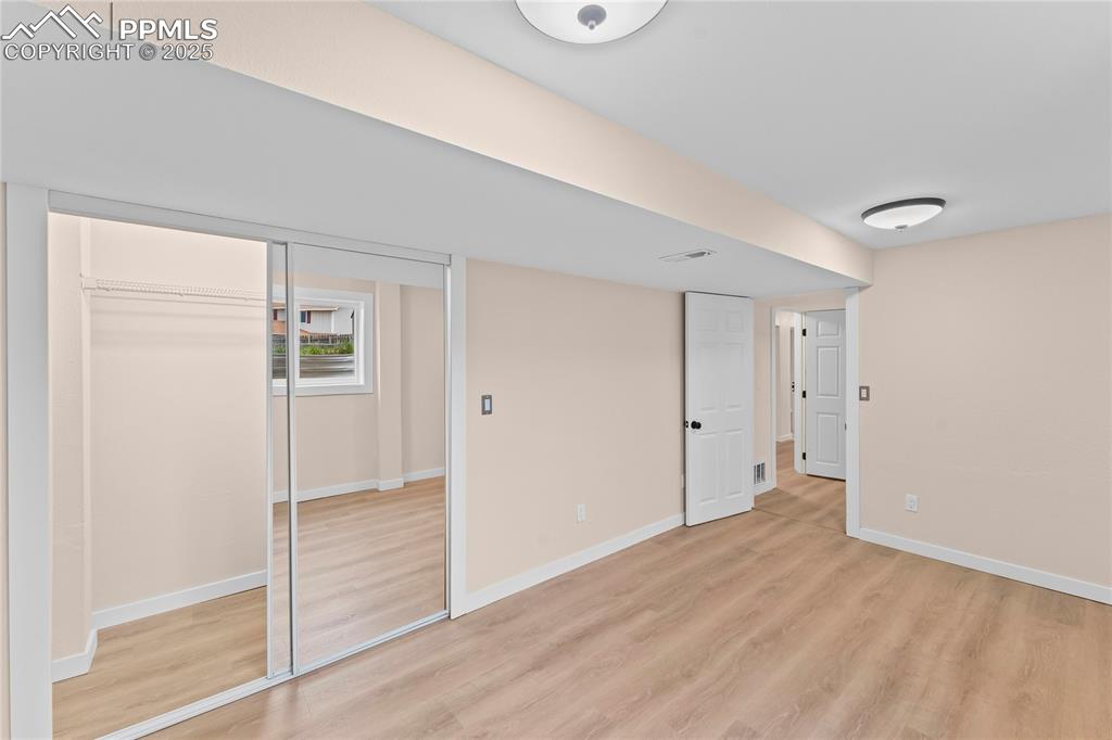 Image 19 of 34: Basement bedroom 1 featuring light wood finished floors and a closet