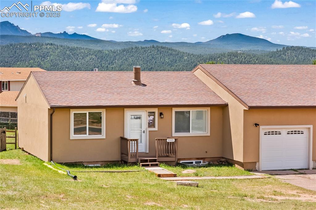 Image 28 of 34: Multi unit property with a mountain view, an attached garage, roof with shi