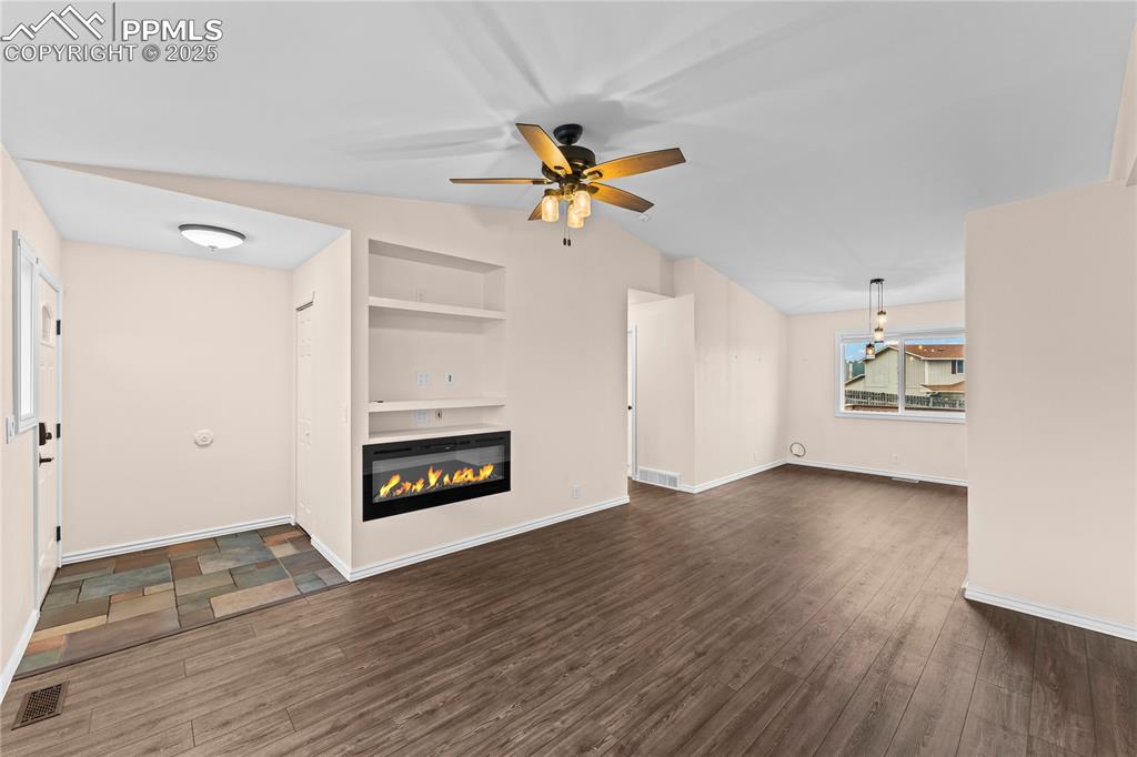 Image 4 of 34: Unfurnished living room with built in features, a ceiling fan, wood finishe