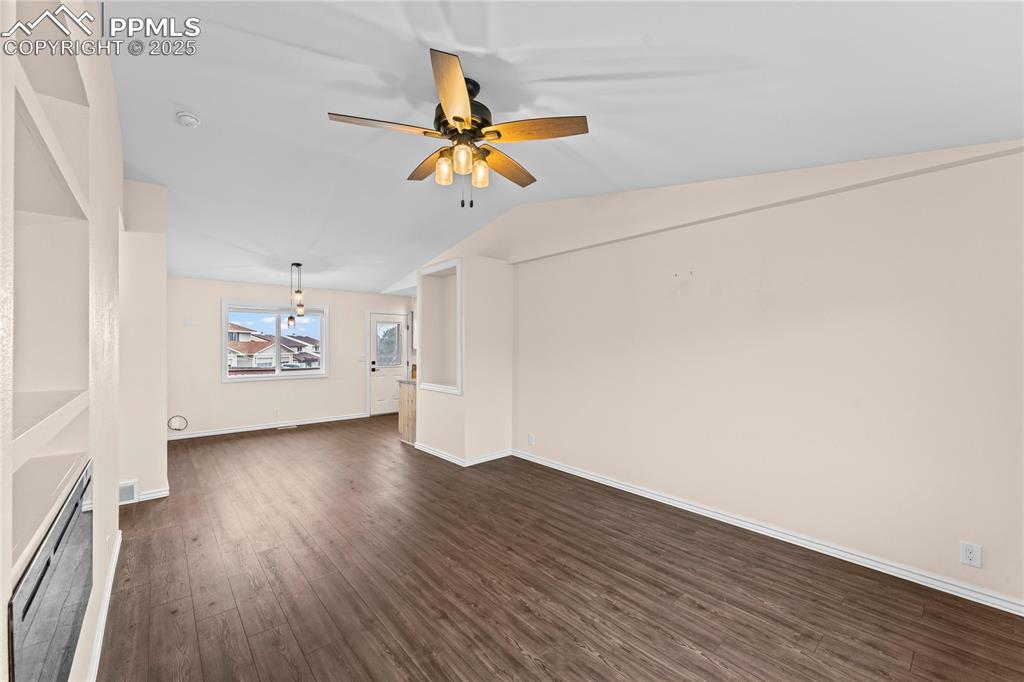 Image 5 of 34: Unfurnished living room featuring dark wood-type flooring, ceiling fan, and