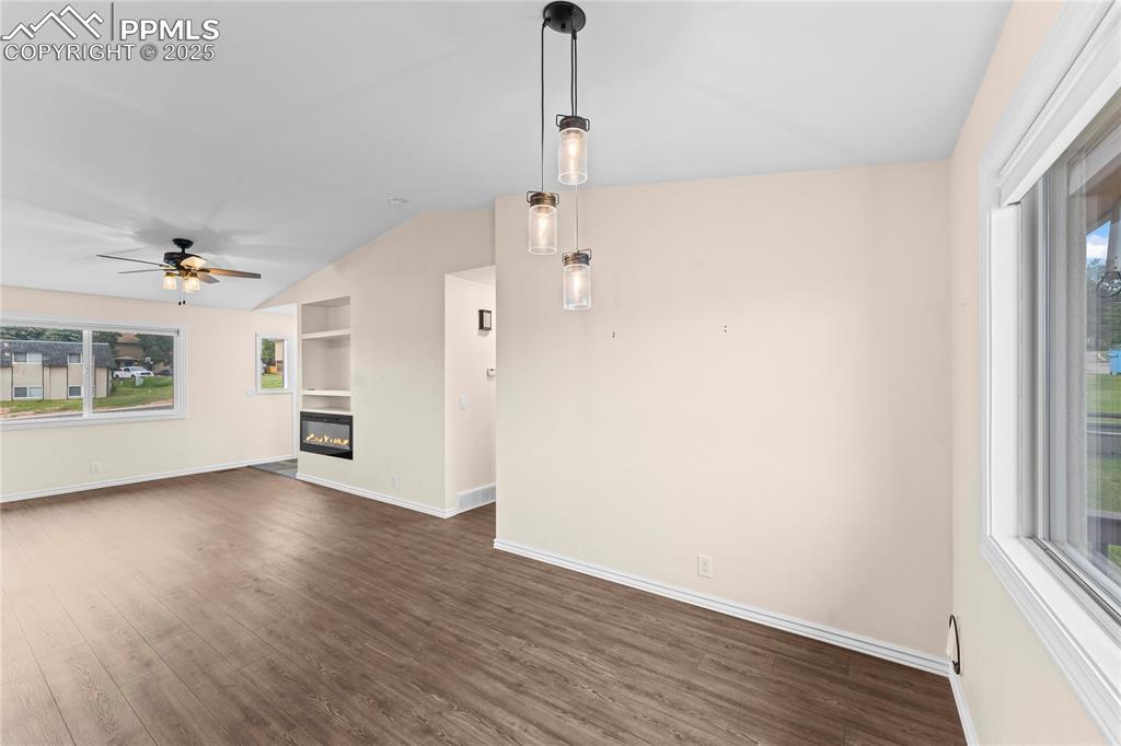 Image 6 of 34: Unfurnished living room featuring vaulted ceiling, plenty of natural light,